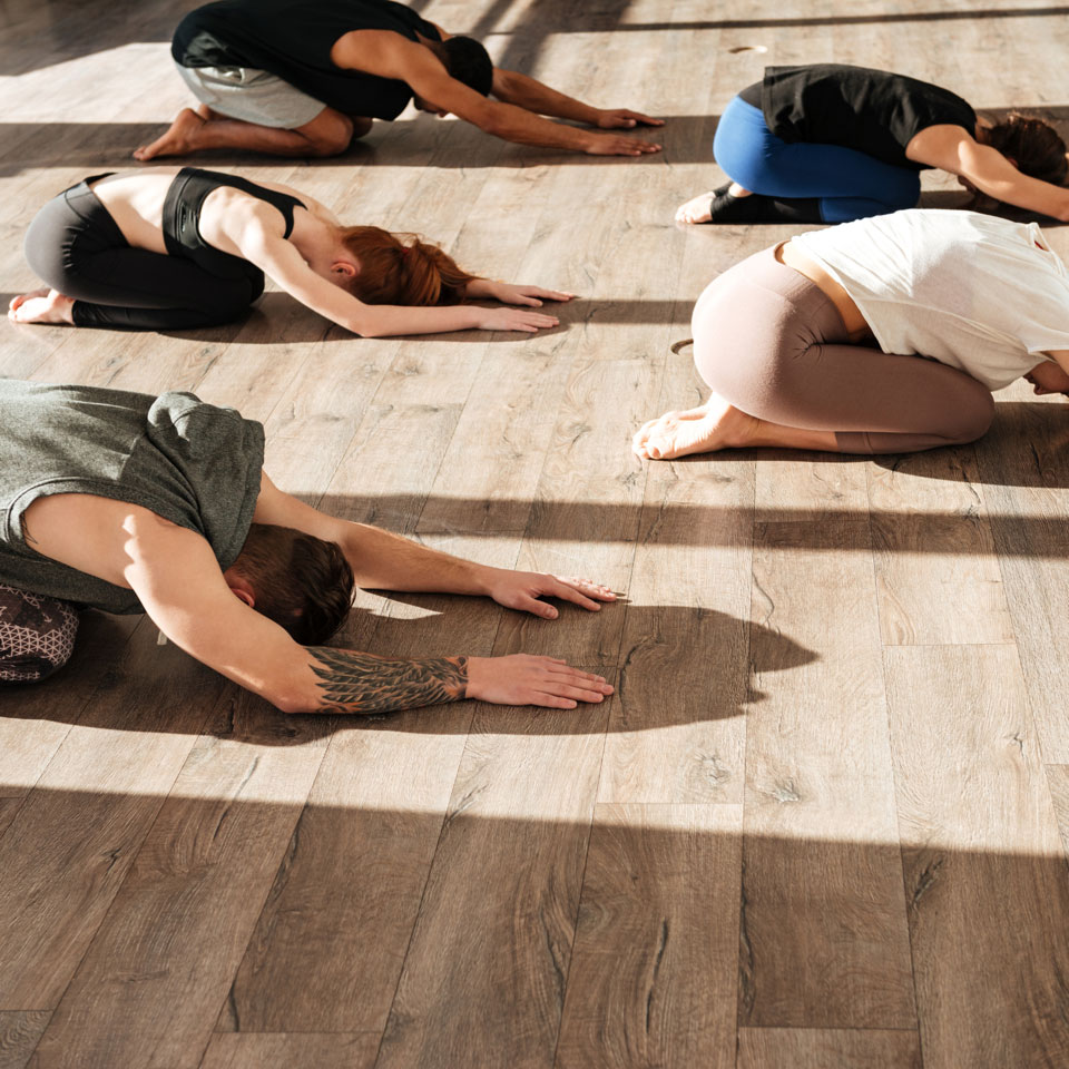 Yoga practitioners stretching on wooden floor
